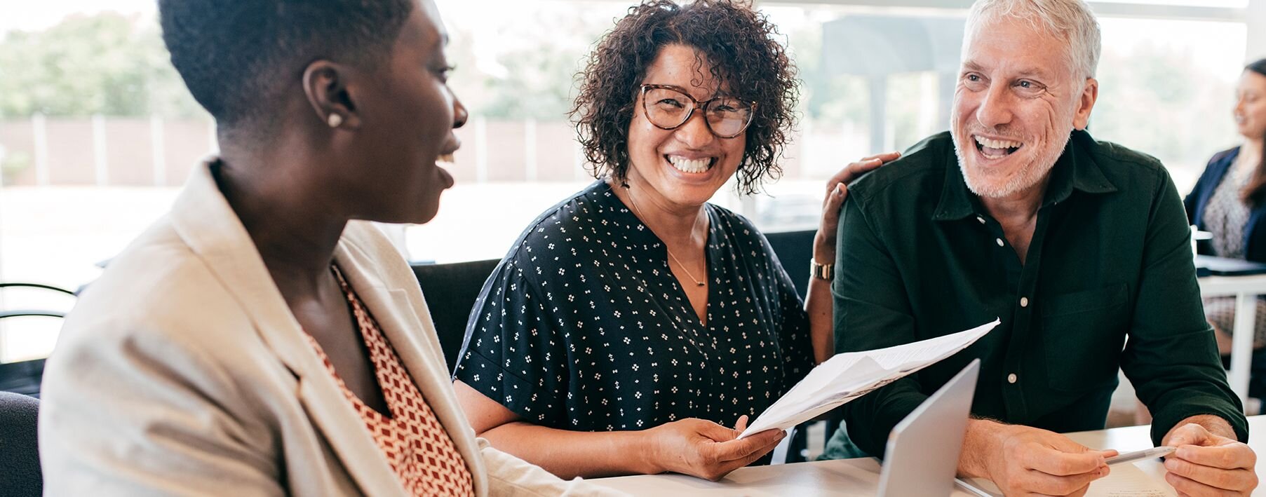 A couple smiling and laughing talking to a woman in a suit