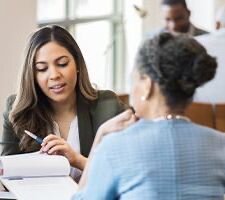 Two women sit at a desk.