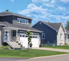 Image of a street with several houses next to each other and a blue sky behind them