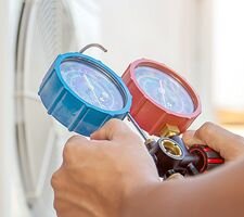 A person's hands using a tool to check an air conditioning unit outdoors
