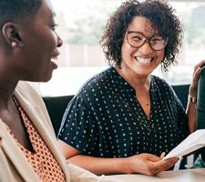 A couple smiling and laughing talking to a woman in a suit