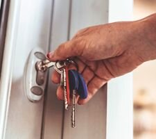 A woman's hand using keys to unlock her front door