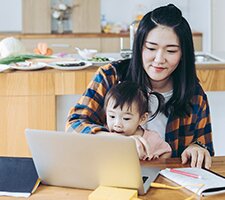 A mom and child using a laptop at the kitchen table