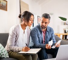 A man and a woman looking at receipts on a couch
