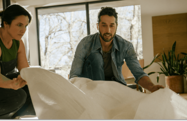 couple putting down a tarp on the floor to get ready for a home renovation